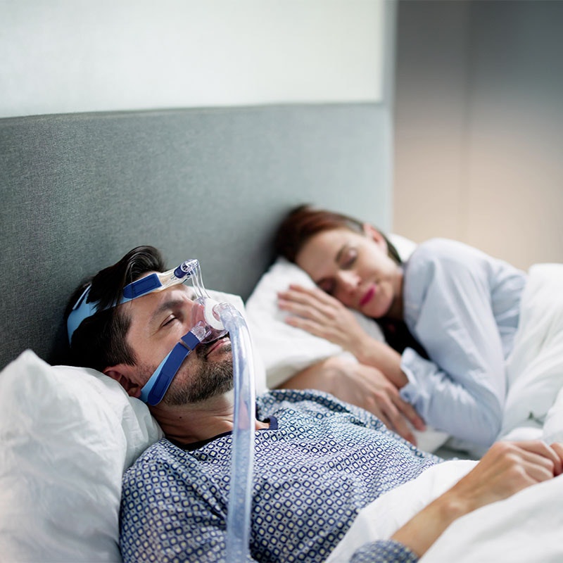 Man sleeping and wearing a CPAP mask next to partner