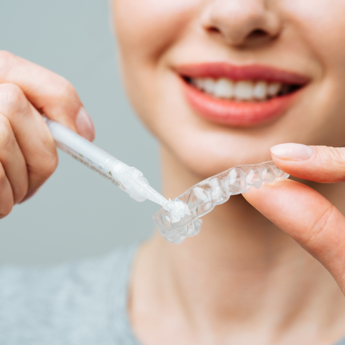 Woman applying gel into a Teeth Whitening tray