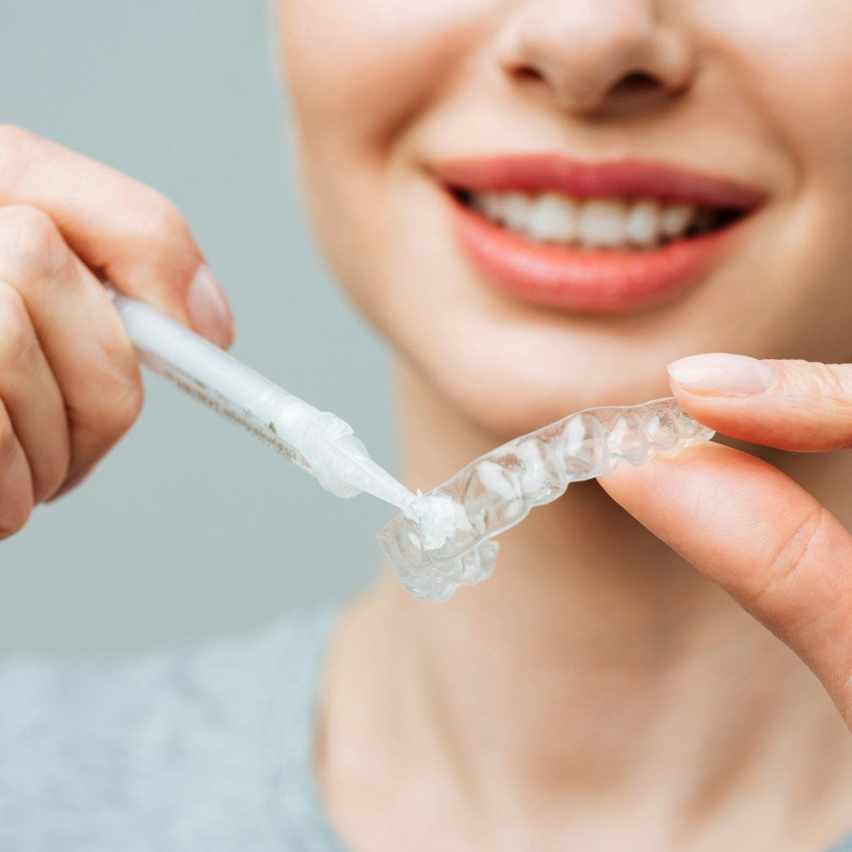 Woman applying gel into a Teeth Whitening tray