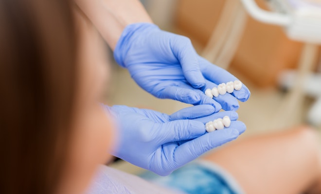 close-up of hands holding a dental bridge
