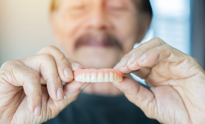 man holding out denture