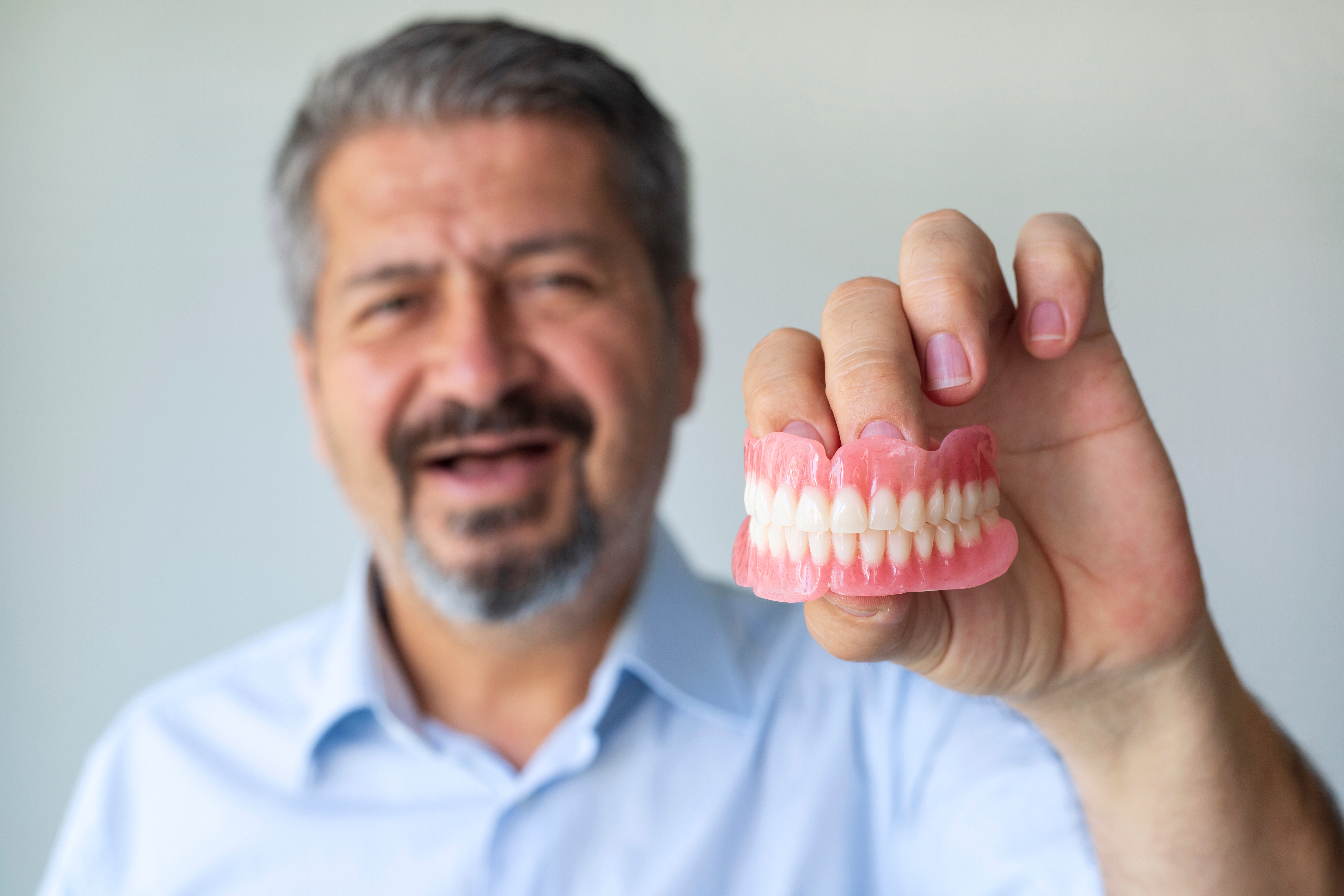 man-holding-out-dentures