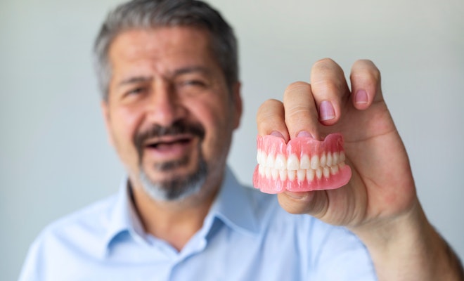 man-holding-out-dentures
