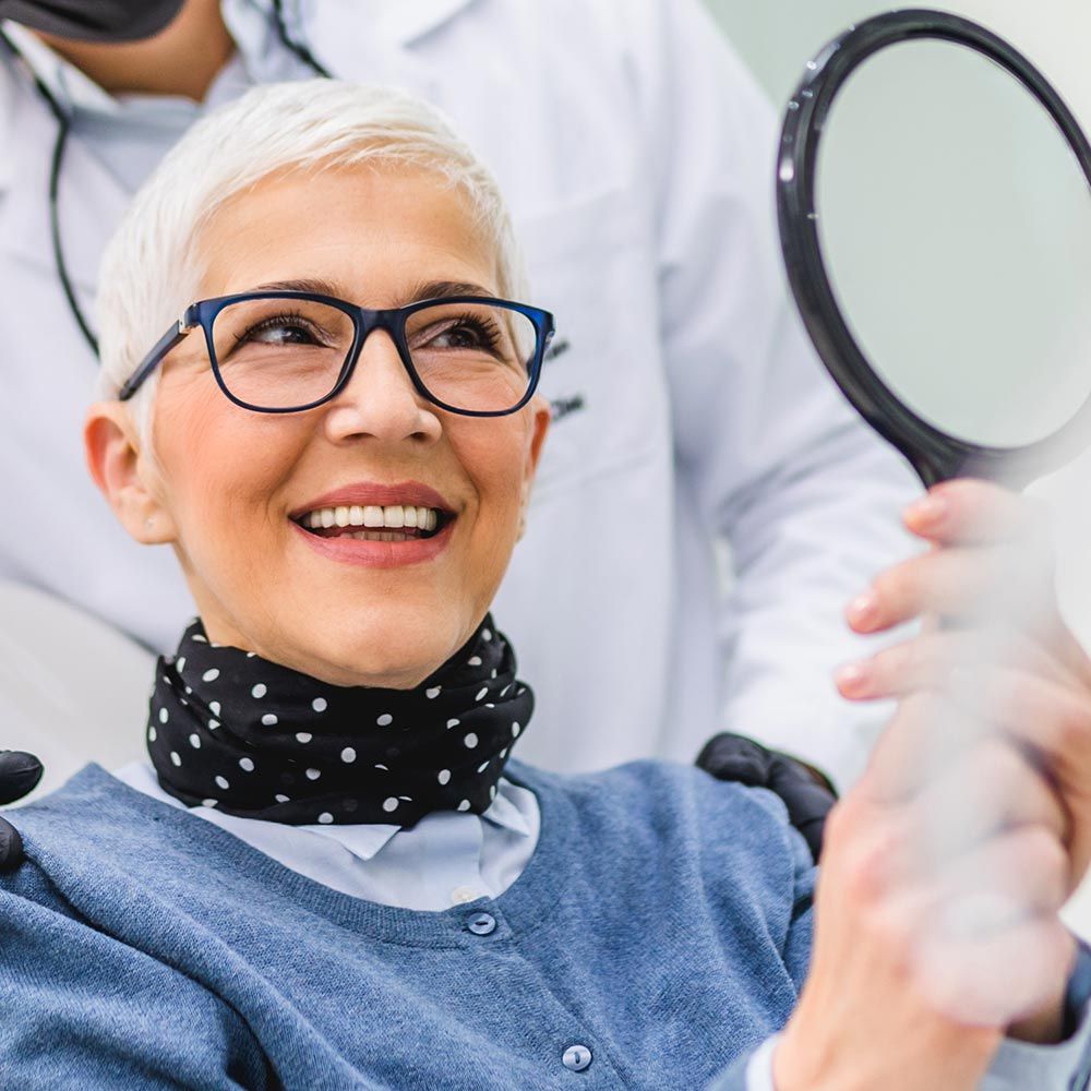 Woman examining new teeth at the dentist's office