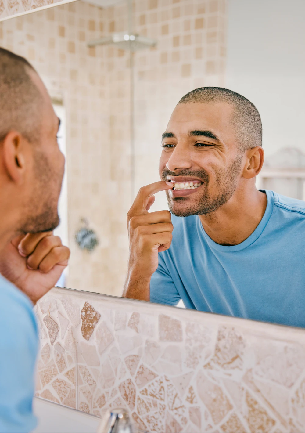 Man smiling at his reflection in a bathroom mirror