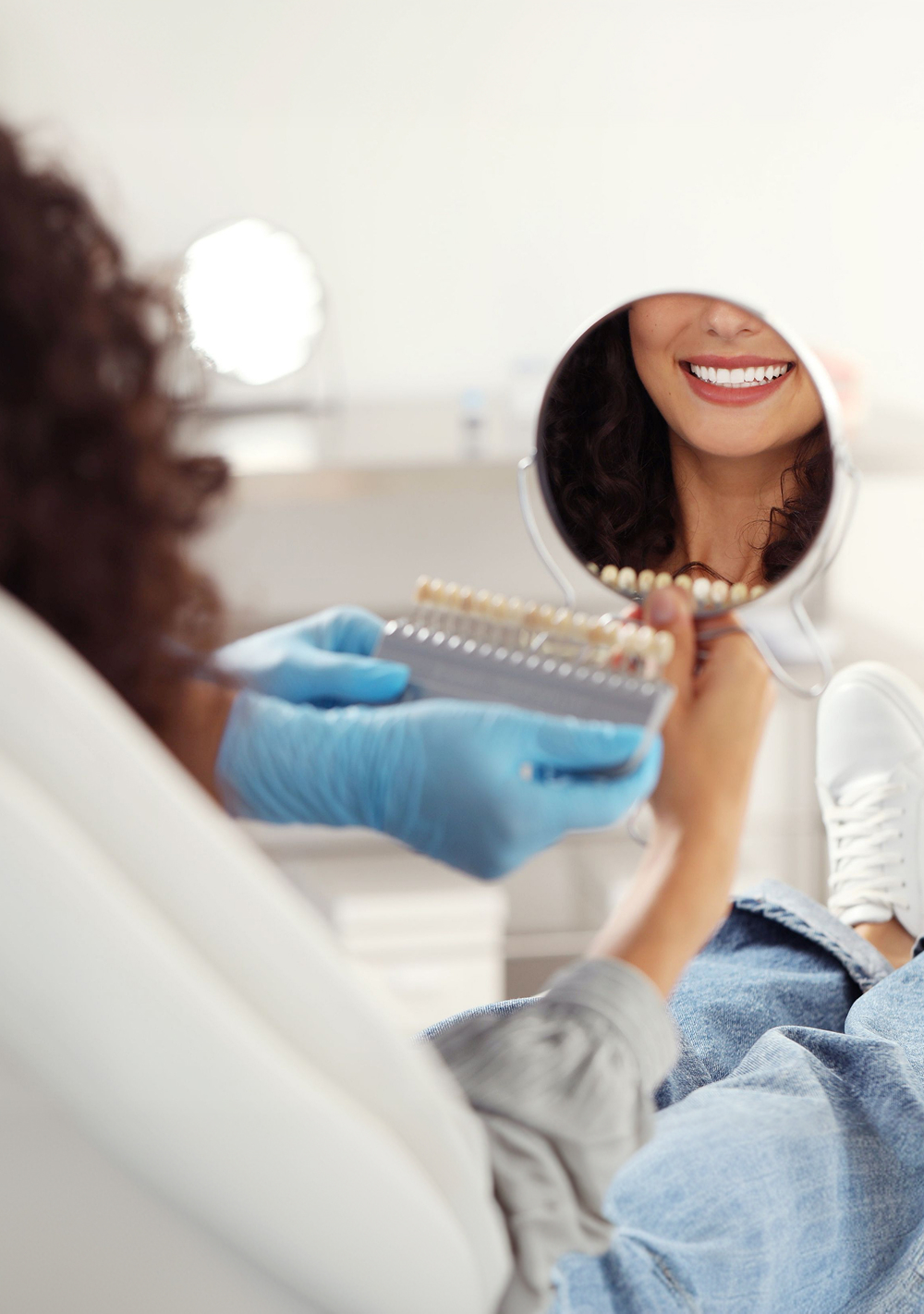 Dental professional holding a veneer shade guide next to a smiling female patient