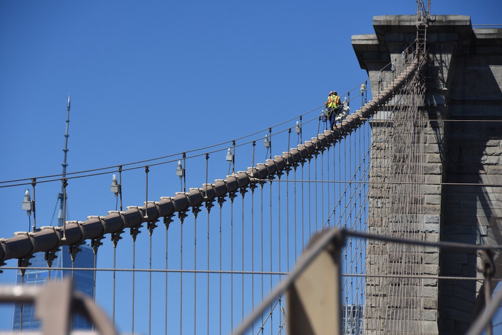 Construction worker walking up the Brooklyn bridge
