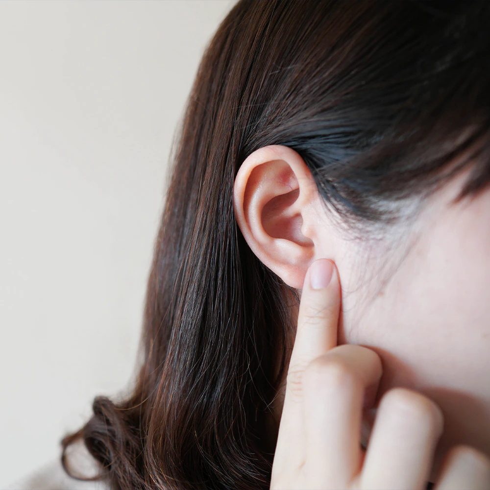 Woman pointing to ear after otoplasty procedure