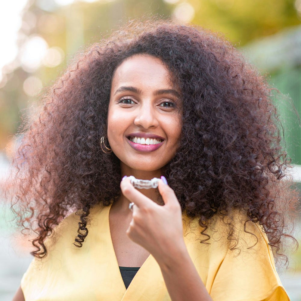 Smiling woman holding Invisalign