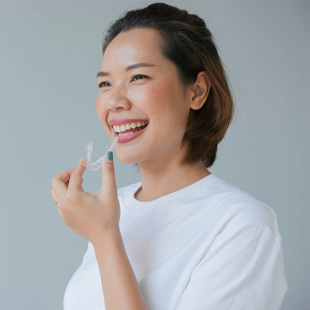 Smiling Woman Holding Invisalign Aligner