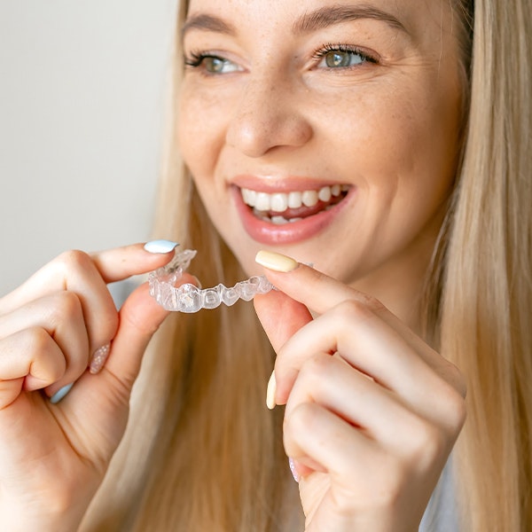 a young woman holding Invisalign appliance