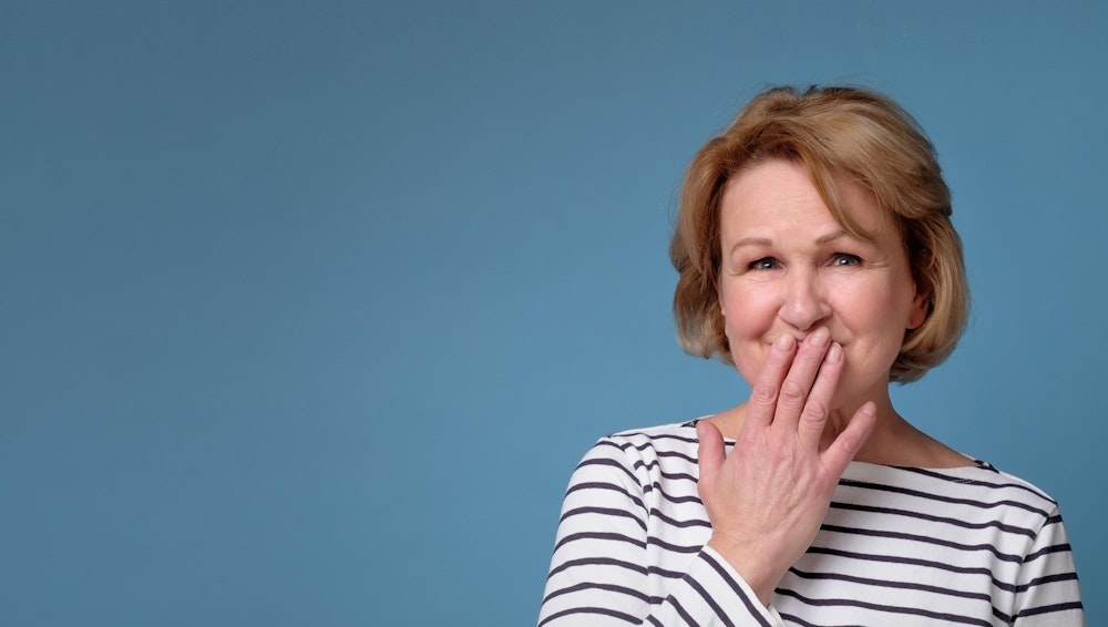 Older woman hiding smile with hands