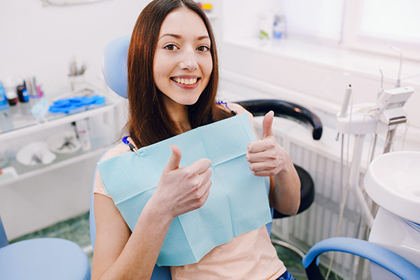 woman giving thumbs-up in dental chair
