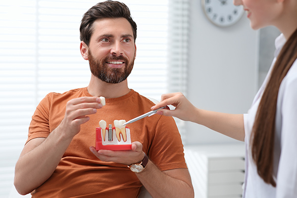 doctor showing patient a dental implant model