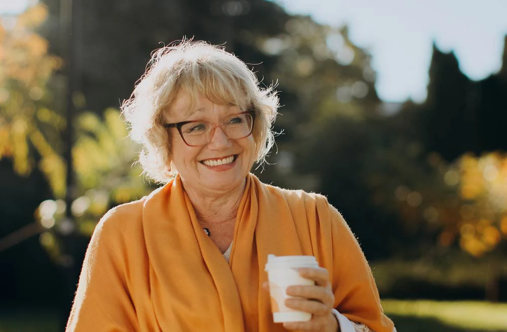 older woman smiling holding a coffee cup