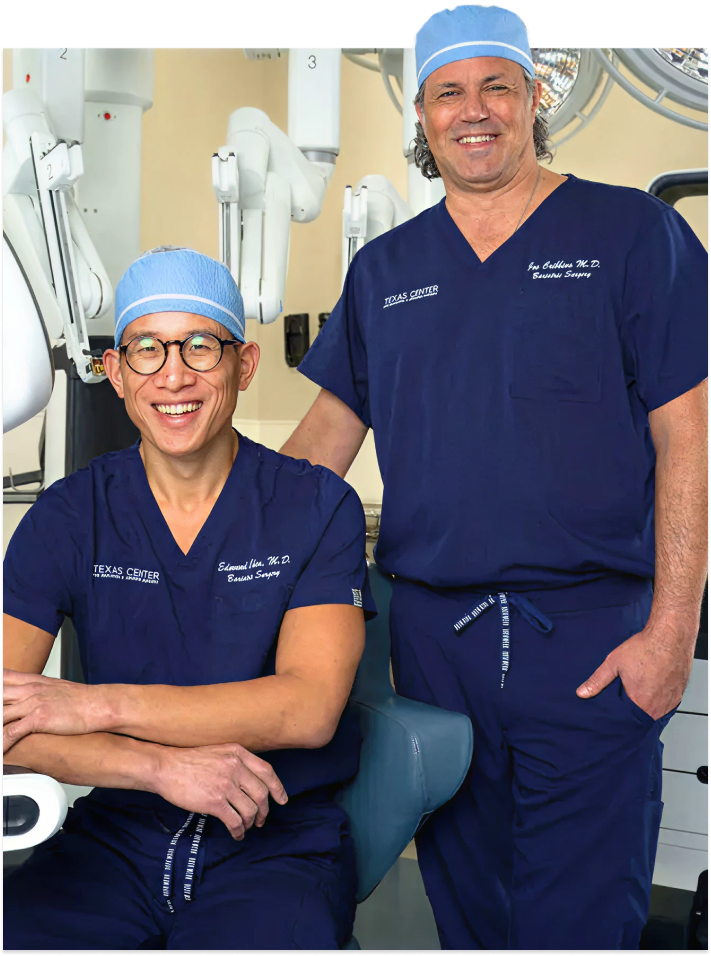 Dr. Edmund B. Chen seated and Dr. A. Joseph Cribbins III standing in surgical scrubs with robotic equipment in the background