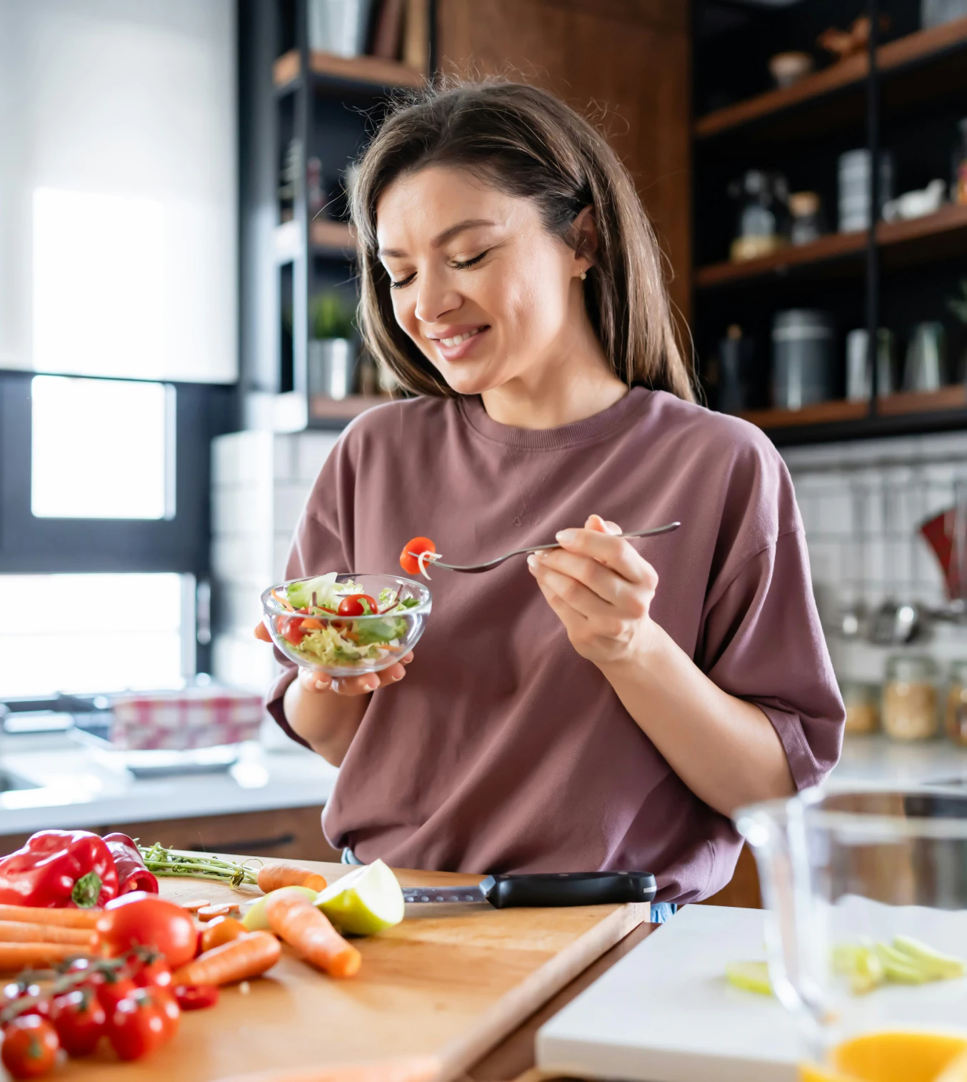 Woman eating salad in kitchen