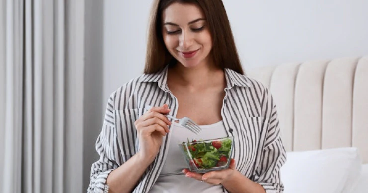 Pregnant woman eating a healthy salad at home