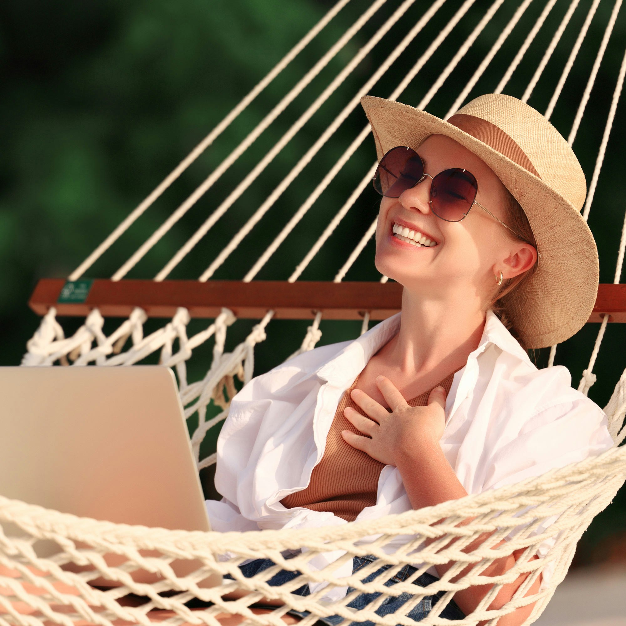 Smiling woman on laptop in hammock