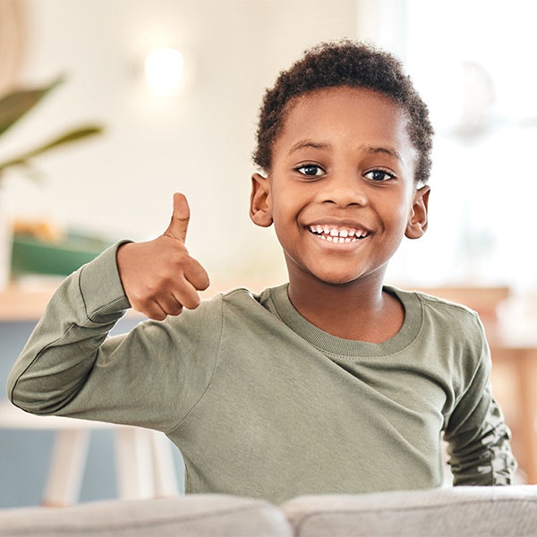 Young boy smiling while giving a thumbs up