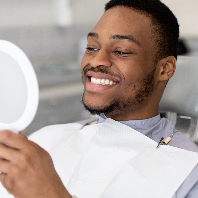 happy man looking at mirror in dentists chair