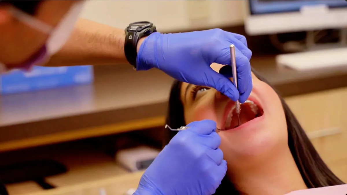 A dentist examines a patient’s teeth during a routine cleaning and exam