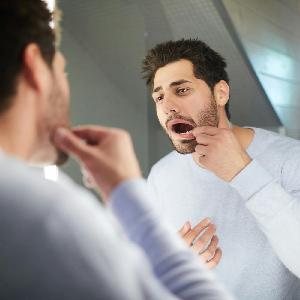 Man looking in mirror to check his tooth