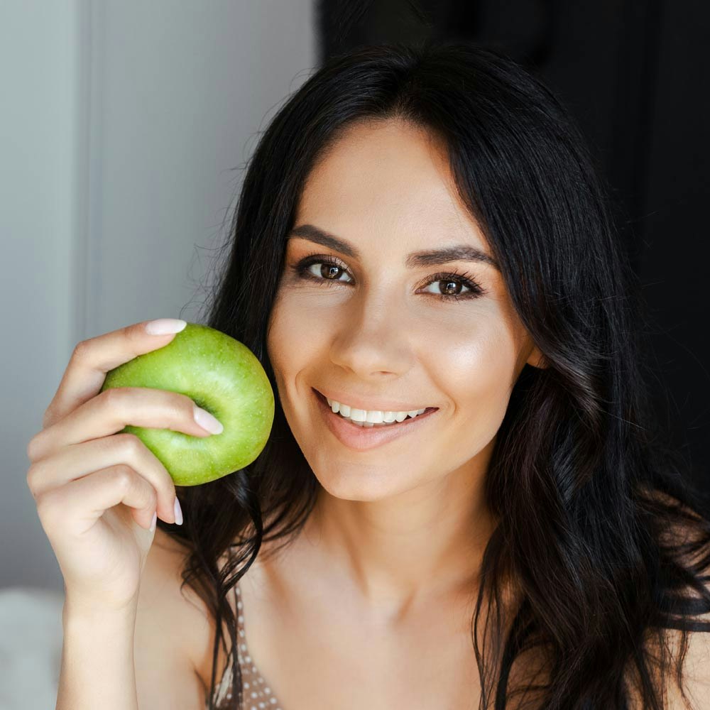 Smiling woman holding green apple