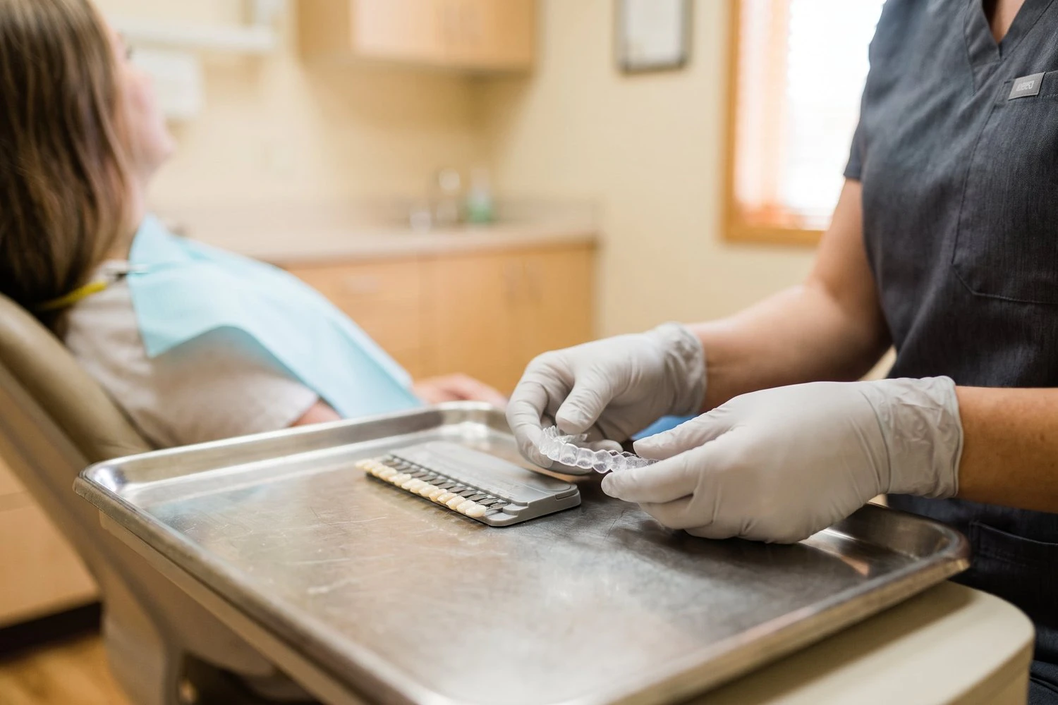 Dental professional holding a custom whitening tray beside a shade guide at Dearborn Family Dentistry