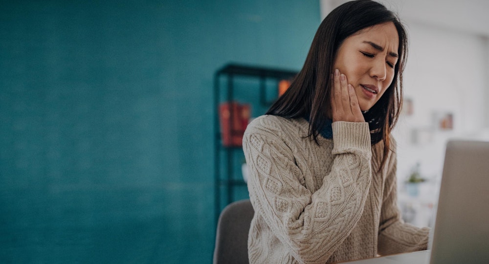 woman holding jaw in pain