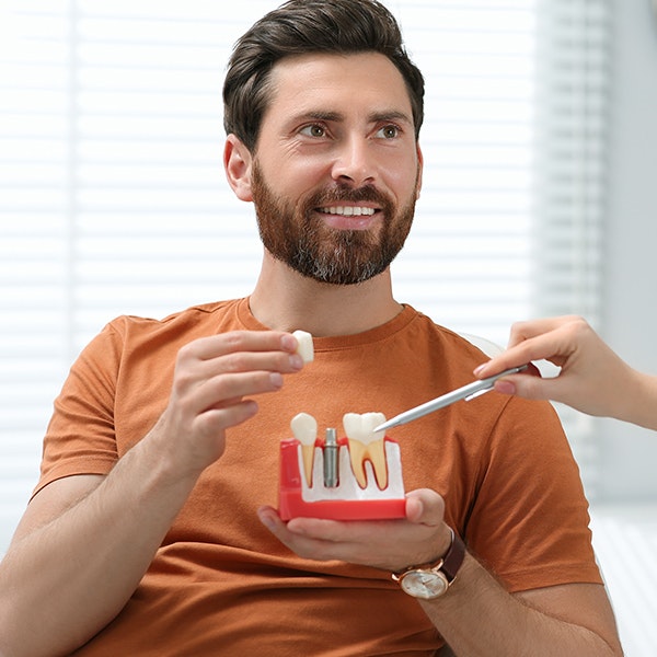 man holding a dental implant