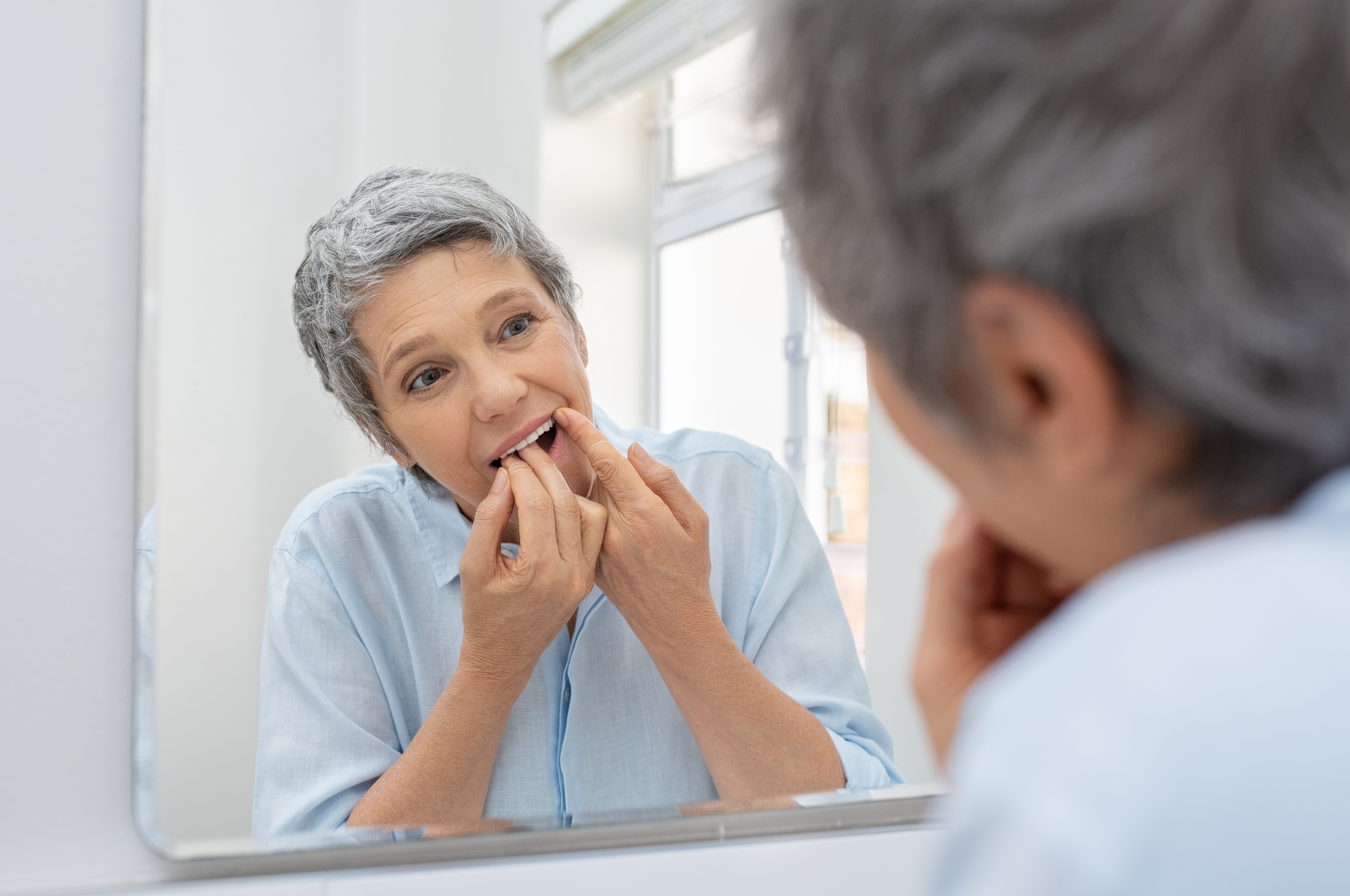 Mature woman flossing her teeth