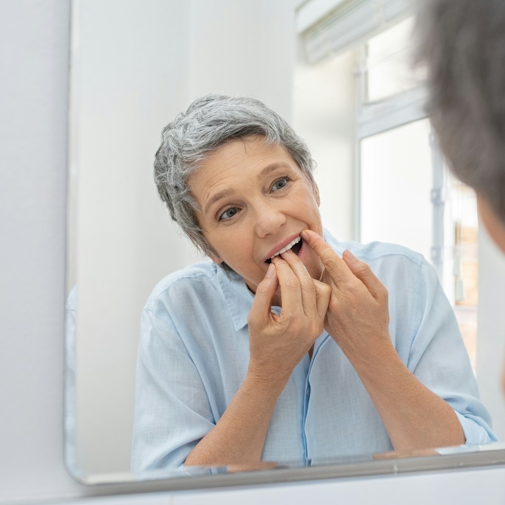 Mature woman flossing her teeth