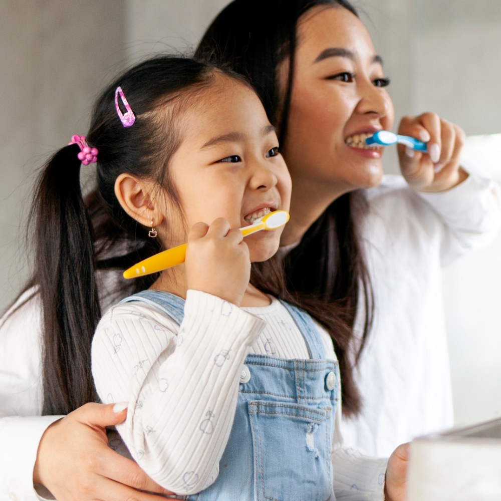 A woman with veneers and daughter brushing teeth