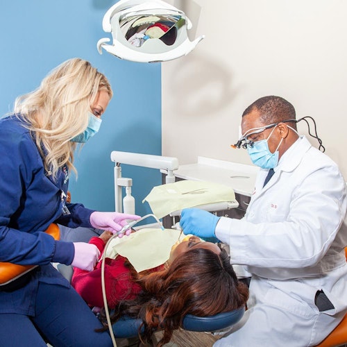 Dr. Saccoh working with another dentist to check patient's teeth