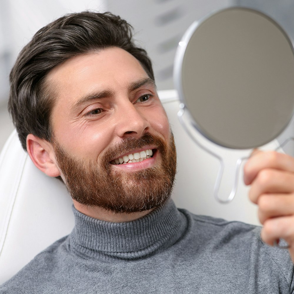 a man looking at his teeth in a mirror
