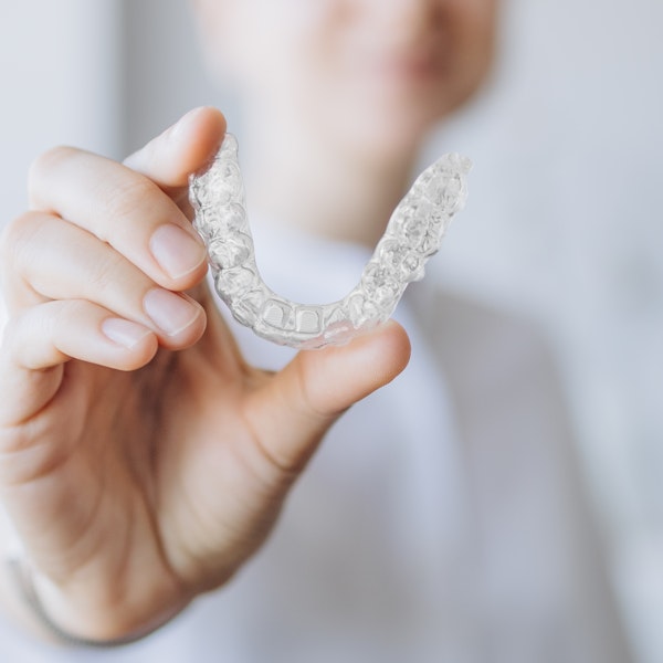 Person holding out an Invisalign aligner