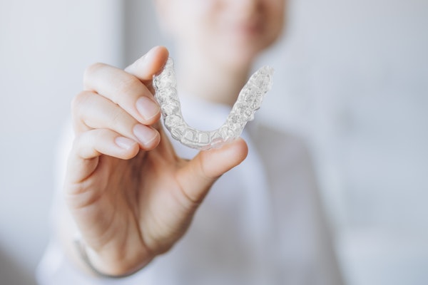 Person holding out an Invisalign aligner