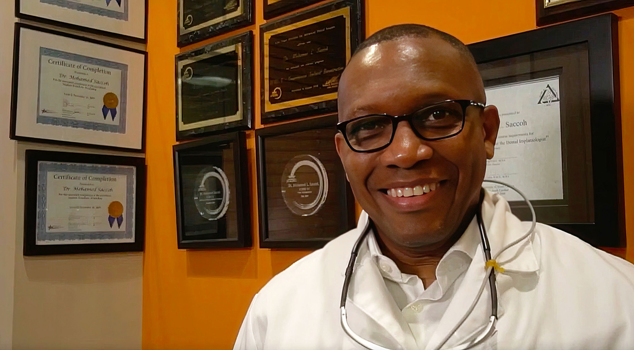 Dr. Saccoh in front of accolades