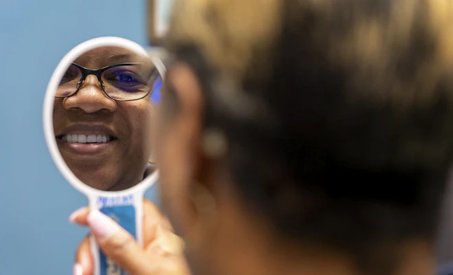 Woman smiling in handheld mirror