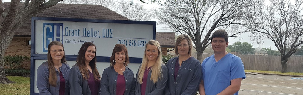 Dental team standing in front of sign outside