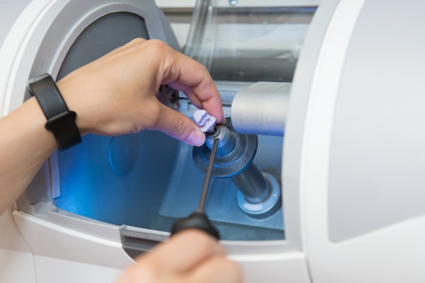 Person placing a block of porcelain into CEREC machine