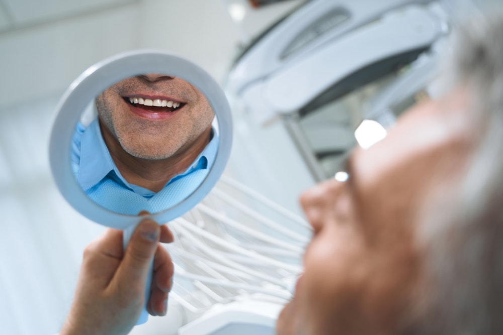 man smiling in a handheld mirror