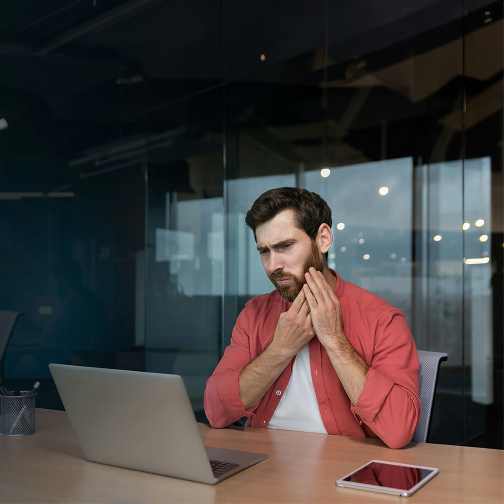 Man who needs a root canal holding his jaw in pain while at work