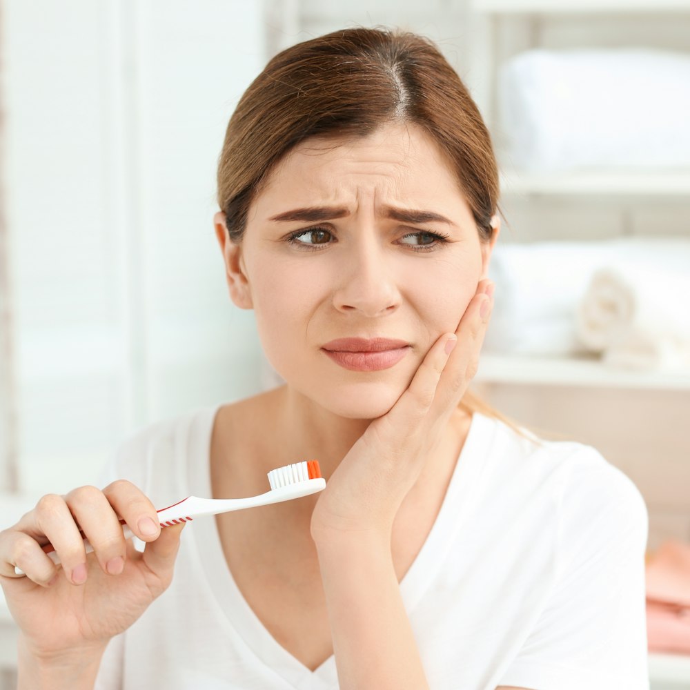 woman brushing teeth with jaw pain