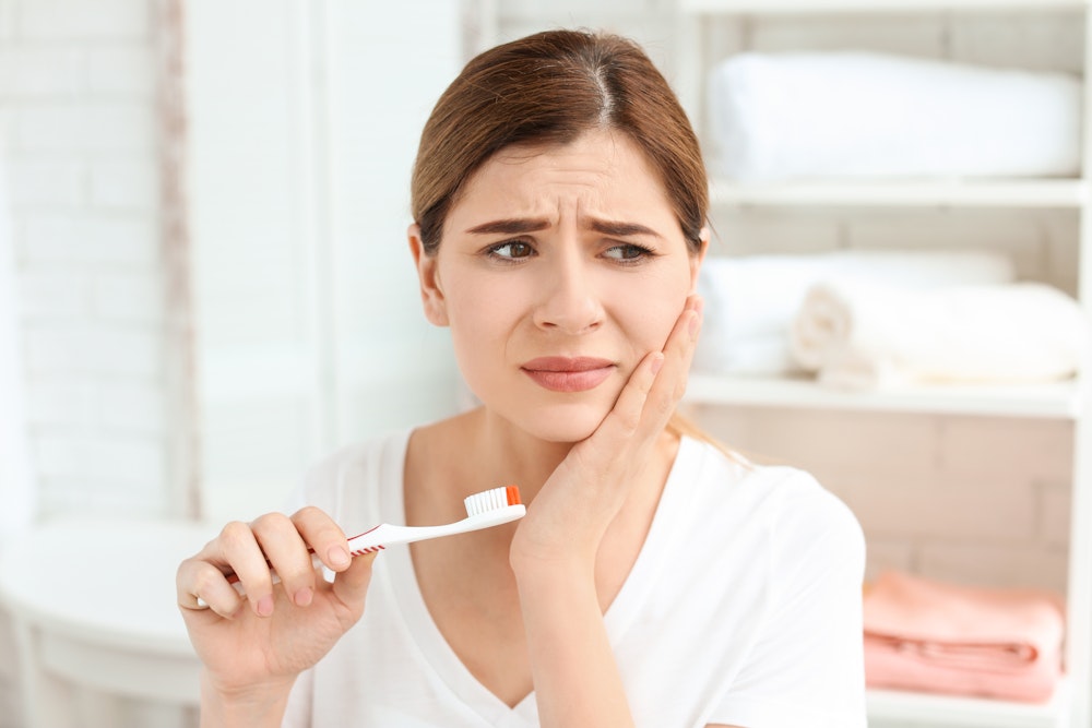 woman brushing teeth with jaw pain