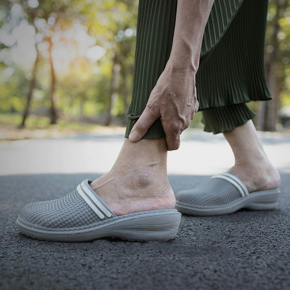 Woman with cane holding ankle