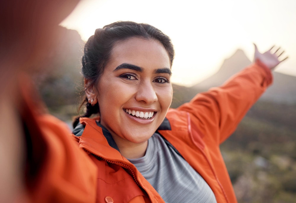 Smiling woman posing while hiking and taking a selfie