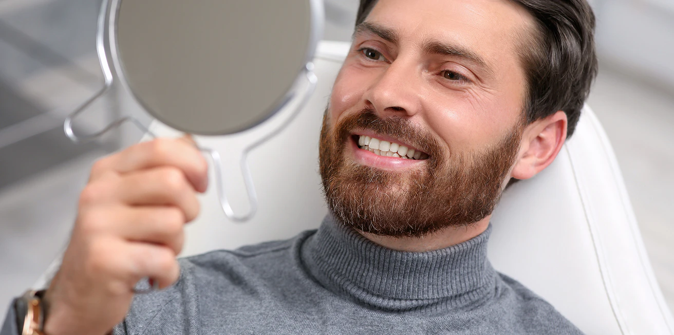 dental patient admiring his smile in the mirror