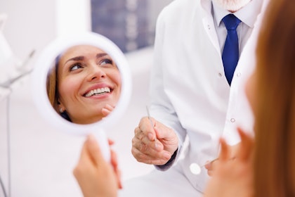Woman smiling in a mirror at the dentist